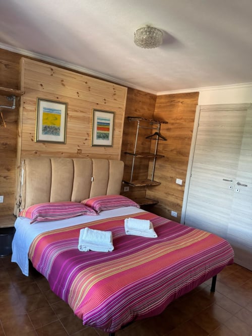 Cozy bedroom at Sormano 4 Apartment with wooden walls, striped red bedding, and mountain views in THE V Collection hotel.