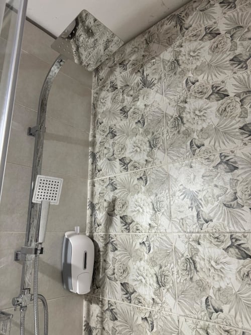 Modern shower in Sormano 4 Apartment with floral tile walls, rainfall showerhead, and white soap dispenser
