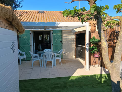 Patio du Gîte des Gônes avec salon de jardin blanc, volets verts et toiture en terre cuite à Feyzin