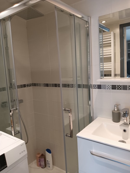 Salle de bain moderne à la villa Gîte des Gônes avec douche vitrée, vasque blanche et frise carrelage décoratif