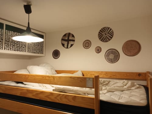 Lit superposé rustique en bois avec draps blancs à la villa Gîte des Gônes, décoration en paniers tressés et luminaires suspendus