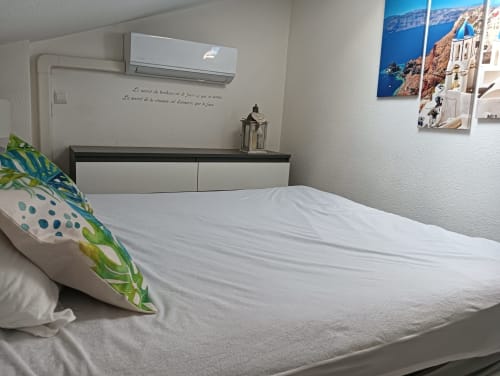 Chambre moderne du Gîte des Gônes avec lit blanc, climatisation et décoration inspirée de Santorin