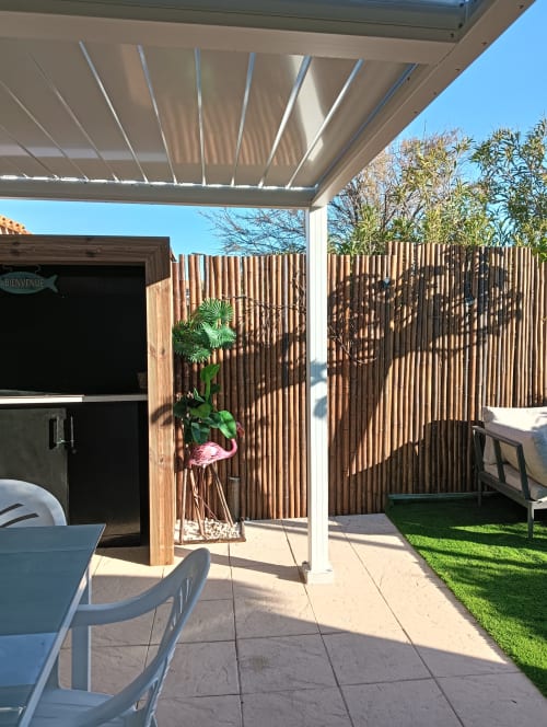 Terrasse moderne avec voile d'ombrage rétractable à la villa Gîte des Gônes à Feyzin, clôture de jardin en bois et vue sur le jardin