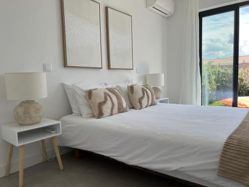 Quarto moderno e luminoso na villa Casa Beliche, Bordeira com vista para o mar, roupa de cama branca, almofadas listradas, mesa de cabeceira em madeira