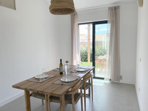 Sala de jantar moderna na vila Casa Beliche com mesa de madeira, vista para o mar através de portas de vidro e vistas do jardim em Bordeira