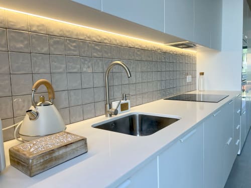 Cozinha moderna com bancada branca, backsplash em azulejo cinzento e pia em aço inoxidável na villa Star Host em Bordeira