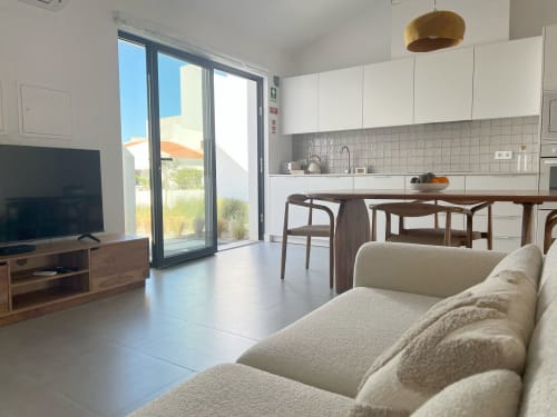 Sala de estar moderna com sofá bege, vista para o mar, sala de jantar e cozinha aberta na Casa Telheiro, Bordeira