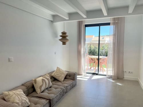 Sala de estar de villa moderna em Bordeira com sofá bege, luminária pendente e vista para o mar através de portas de vidro