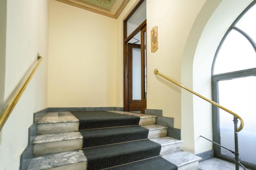 Elegante scala con tappeto nero e corrimano in ottone nell'ingresso di un edificio residenziale a Roma