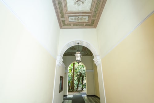 Elegante corridoio con volta in appartamento romano, soffitto decorato, che conduce a un giardino cortile tropicale e ingresso separato