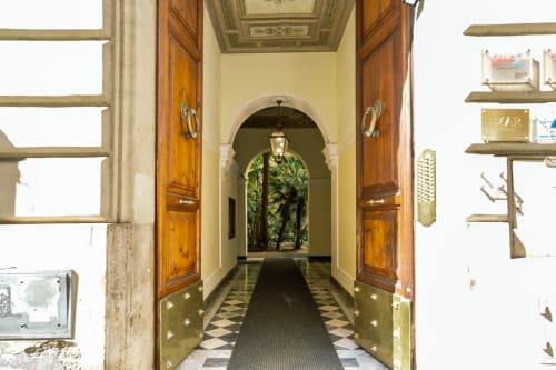 Elegante ingresso di Casa Verde di Astrachan a Roma con porte in legno, pavimento a scacchiera e arco che conduce a