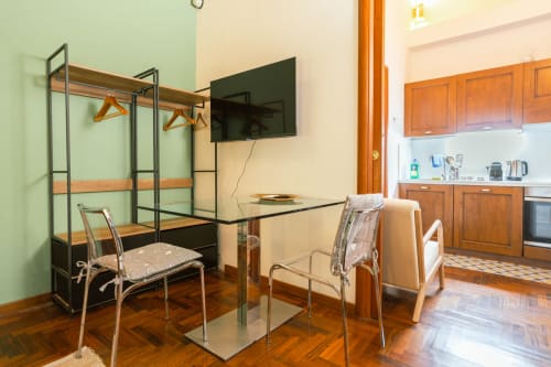 Elegante monolocale a Roma con letto a baldacchino, tavolo da pranzo, cucina, pavimenti in legno e TV a schermo piatto
