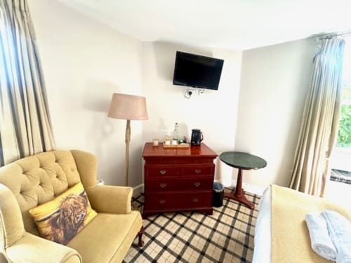 John Martin Superior King Room at The Railway Hotel with yellow armchair, red chest, TV, and river views in Haydon Bridge
