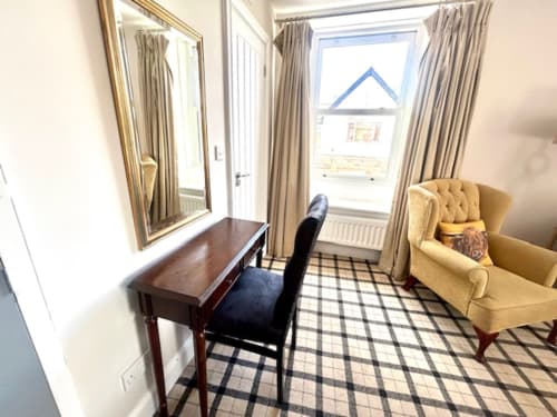Superior King Room at The Railway Hotel Haydon Bridge with desk, beige wingchair, plaid carpet, and river views through