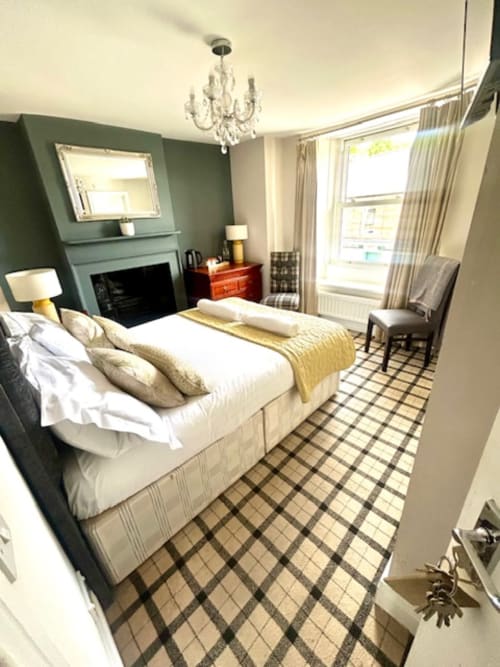 Cookson Deluxe Double Room at The Railway Hotel Haydon Bridge with fireplace, queen bed, and tartan carpet