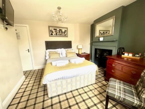 Cookson Deluxe Double Room at The Railway Hotel with yellow accents, green feature wall, double bed, wooden dresser, and
