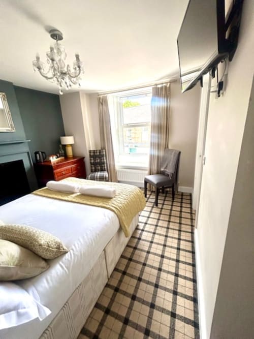 Cookson Deluxe Double Room at The Railway Hotel Haydon Bridge with white bed, yellow throw, teal accent wall, and tartan