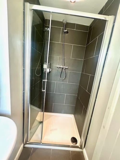 Modern shower enclosure with dark tile walls and white base in Cookson Deluxe Room at The Railway Hotel Haydon Bridge