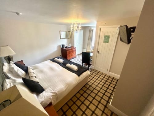 Superior King Room at The Railway Hotel Haydon Bridge with white bedding, black accents, checkered floor, red dresser,