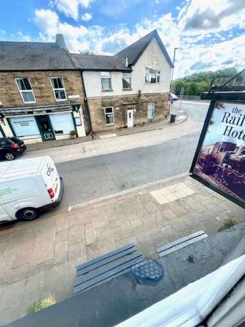 The Railway Hotel Haydon Bridge exterior on Church Street with stone buildings, parked van, and green riverside views in