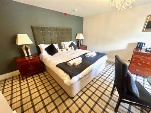 Superior King Room at The Railway Hotel Haydon Bridge featuring a tufted headboard bed with white linens, dark runner, and