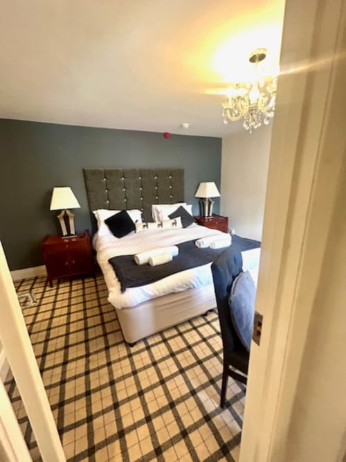 Luxurious superior king bedroom at The Railway Hotel Haydon Bridge with grey headboard, white bedding, and checkered