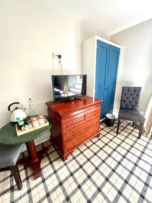 Ratcliffe Superior King Room at The Railway Hotel Haydon Bridge with wooden dresser, TV, blue wardrobe, and plaid carpeting.