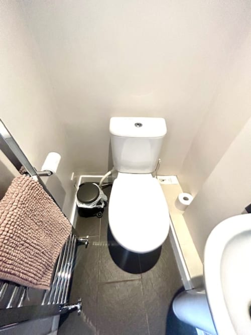 Modern toilet with white seat and dark base in Ratcliffe Superior King Room bathroom at The Railway Hotel Haydon Bridge