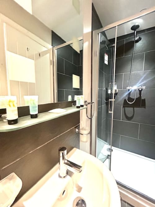 Modern bathroom in Superior King Room at The Railway Hotel Haydon Bridge, featuring dark tile shower, double vanity sink, and