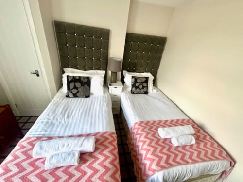 Twin beds with olive headboards, pink zigzag blankets, and decorative pillows at The Railway Hotel Haydon Bridge budget twin