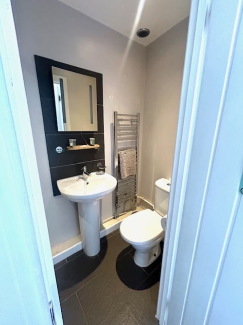 Modern bathroom in Shaftoe room at The Railway Hotel Haydon Bridge with pedestal sink, toilet, mirror, and heated towel rack