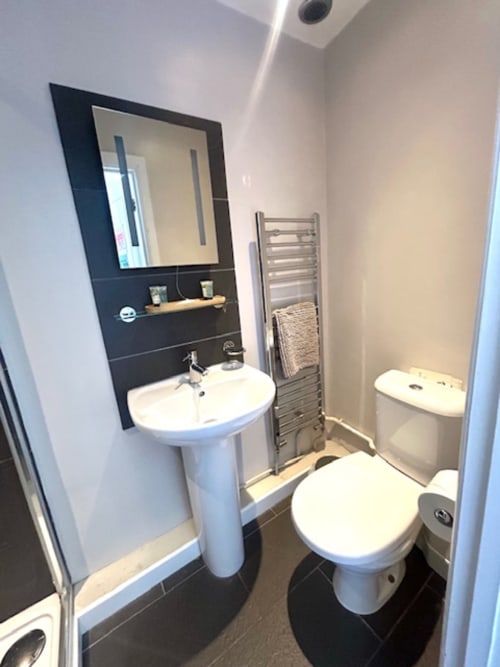 Modern bathroom at The Railway Hotel Haydon Bridge with pedestal sink, toilet, heated towel rack, and black framed mirror