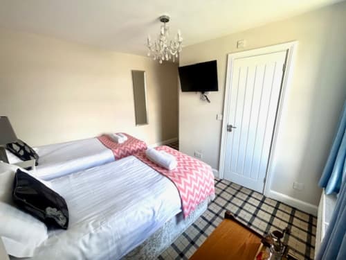 Shaftoe Budget Twin Room at The Railway Hotel Haydon Bridge, featuring two beds, flat-screen TV, chandelier, and checkered