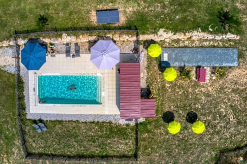 Vue aérienne du gîte Home Sweet Lodge avec piscine turquoise, parasols colorés et terrasse aménagée en Aquitaine, France