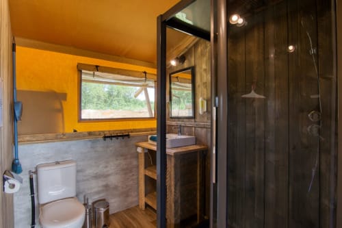 Moderne badkamer in glamping met gele wanden, houten wastafel, donkere douchewand en toilet