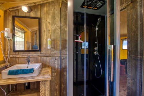Luxe badkamer bij Home Sweet Lodge Glamping met houten wanden, moderne douche en design wastafel