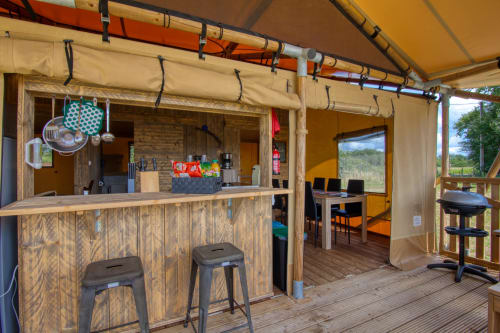 Glamping-tentinterieur met houten bar, krukken en eetgedeelte bij Home Sweet Lodge Aquitaine, Frankrijk