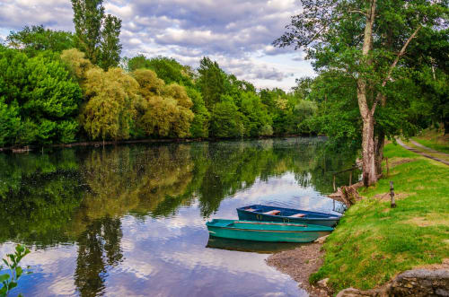 Cadre paisible au bord de la rivière au Home Sweet Lodge Glamping Aquitaine avec des bateaux amarrés sur des eaux calmes