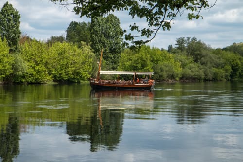 Bateau en bois traditionnel avec passagers sur un fleuve calme entouré de verdure près de Saint Germain et Mons, Aquitaine