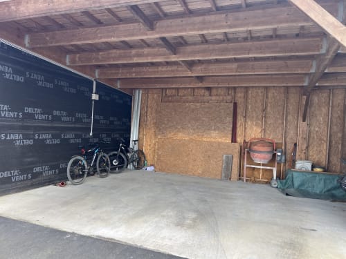 Garage inachevé avec vélos, poutres en bois et matériaux de construction au CafecouetBreizh BnB à Guipry-Messac, France