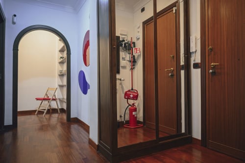 Corridoio moderno dell'hotel romano con volta ad arco, porte in legno, estintore rosso e arte murale colorata