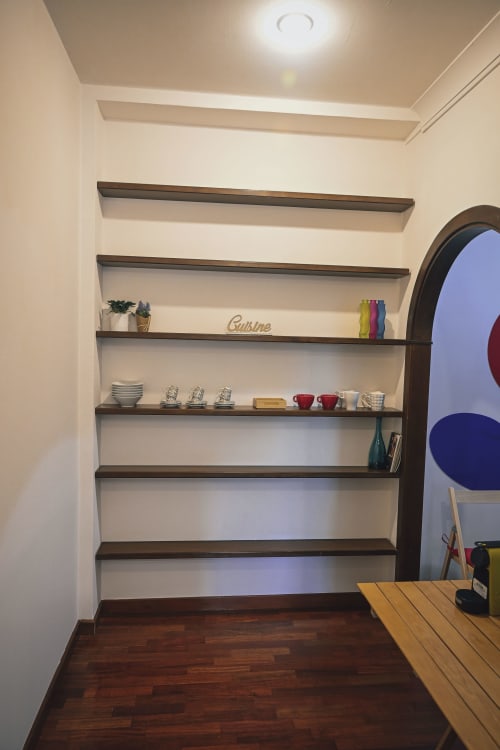 Scaffalature moderne integrate in legno scuro con articoli da cucina e decor in una camera d'affitto a Roma