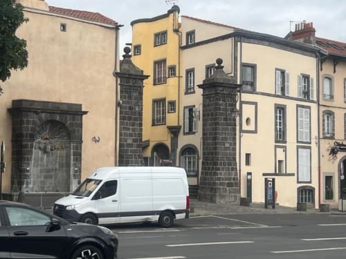 La Caravelle hotel exterior in Riom, France with historic stone architecture and yellow building facade