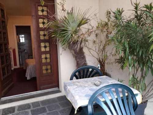 La Caravelle hotel patio in Riom with blue chairs, table, and lush plants against terracotta walls
