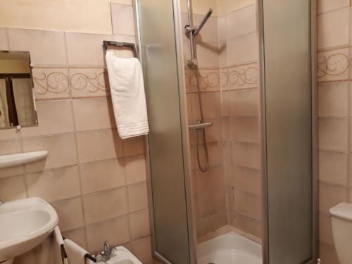 Modern bathroom at La Caravelle hotel in Riom with tiled shower, white towel rack, and contemporary fixtures