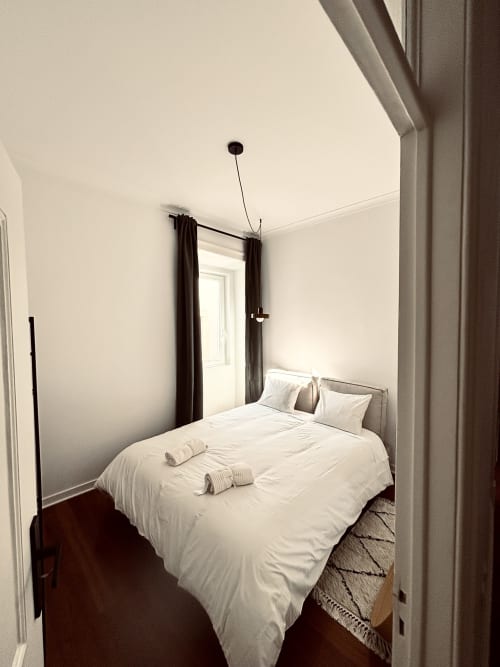 Bright bedroom in Royal Prince Garden Apartments, Lisboa, with white bedding, dark curtains, and minimalist décor