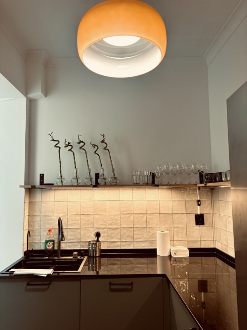 Modern kitchen in luxury apartment at Royal Prince Garden Apartments, Lisbon with black countertop, beige tiles, and orange