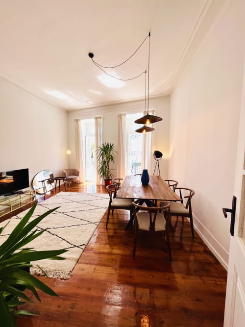 Modern Lisbon apartment with dining table, wooden floors, pendant lights, and city views through balcony doors