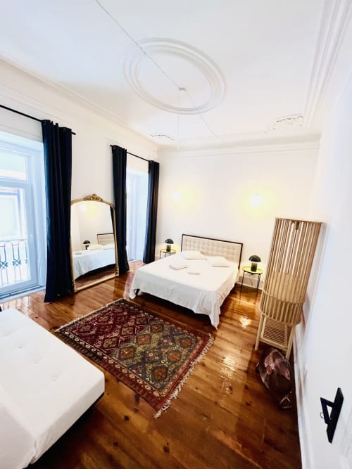 Spacious bedroom in Royal Prince Garden Apartments, Lisbon, with wooden floors, modern bed, ornate mirror, and balcony