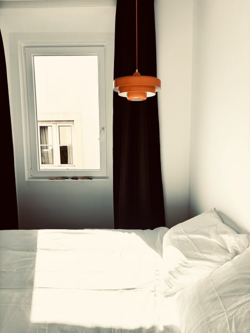 Modern bedroom at Royal Prince Garden Apartments Lisboa with white bedding, orange pendant lamp, and city view window